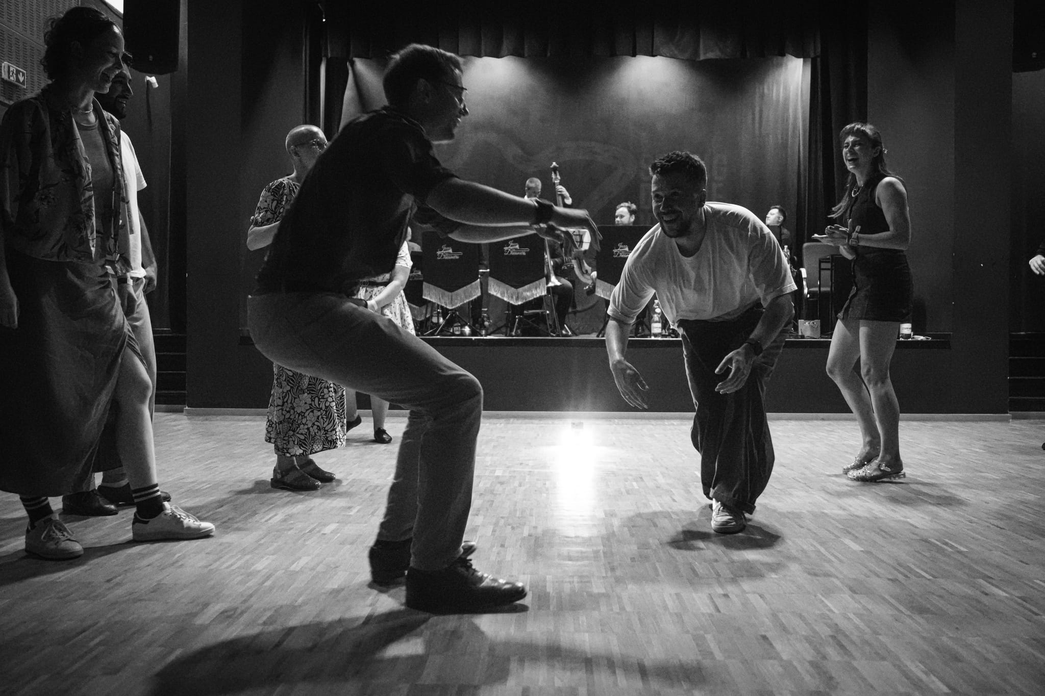 Tancerze w jam circle na potańcówce swingowej, w tle zespół na scenie